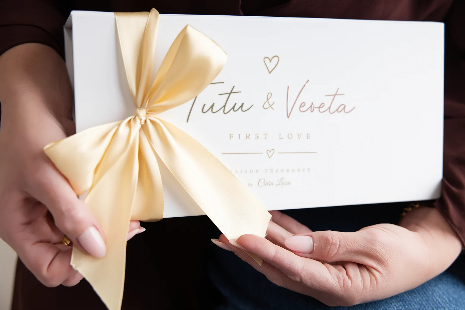 Tutu & Veveta gift box held in the hands, finished with a champagne ribbon