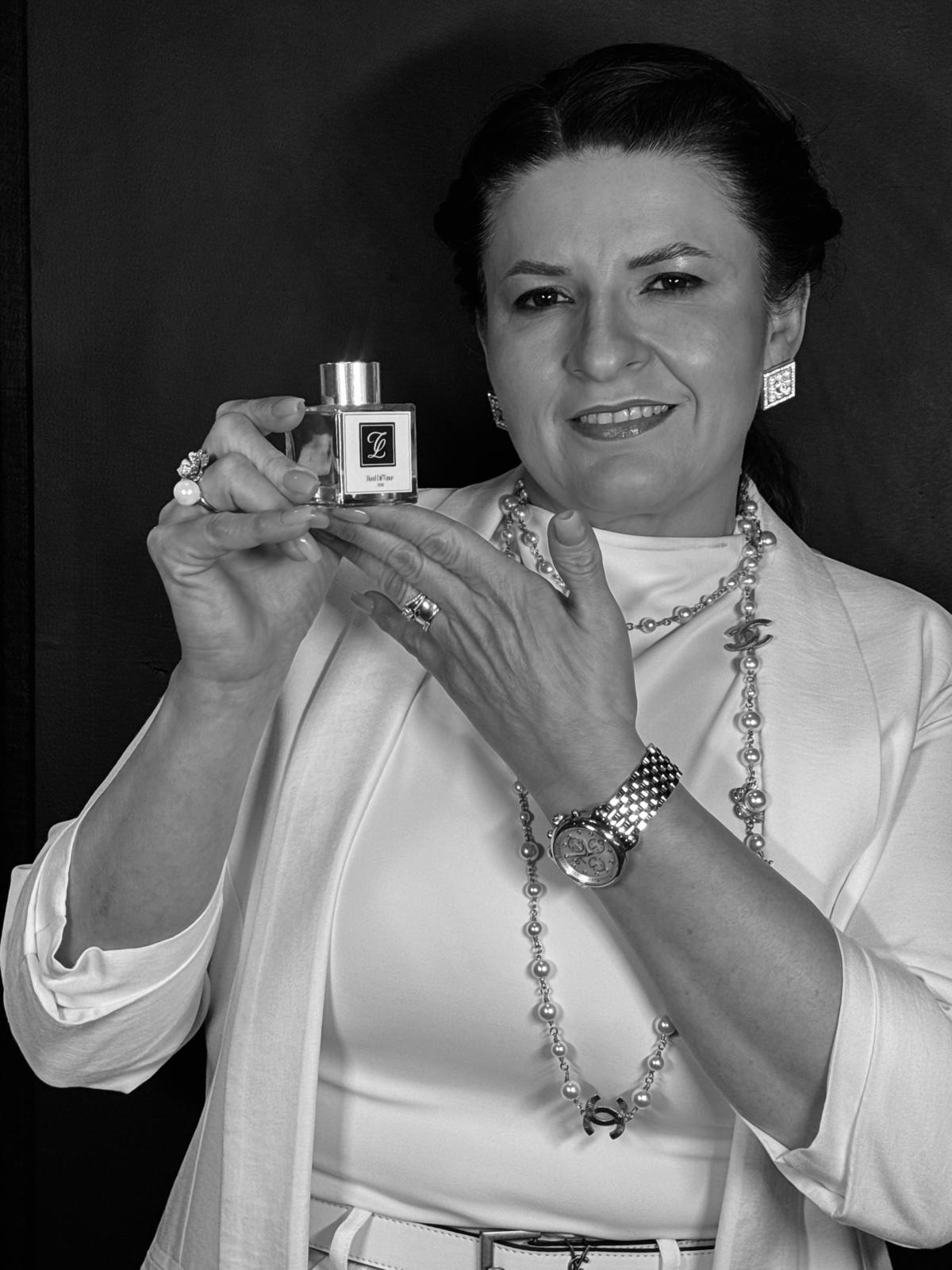 Ciara Lessa holding a Maison fragrance bottle with the CL monogram, in the approved black-and-white portrait.